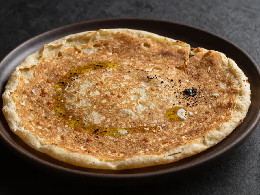 Socca niçoise dorée sur assiette en céramique sombre